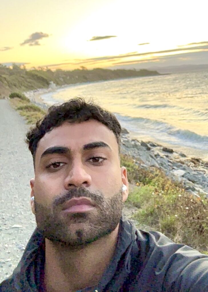 Arsh standing on a coastal trail at sunset